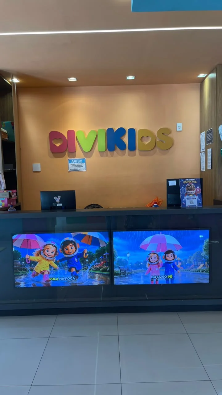 Recepção da loja Divikids com Luna e Leo aparecendo em duas telas